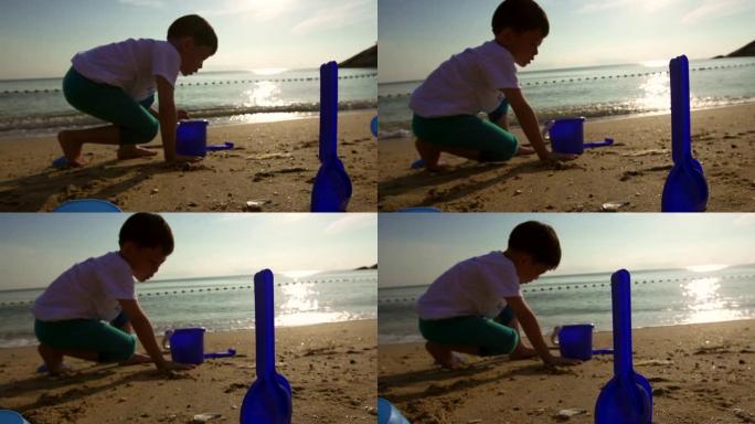 孩子的剪影早上在海滩上玩沙子。