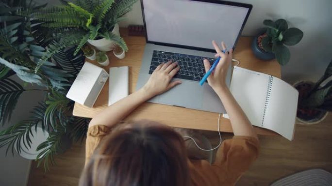 亚洲妇女在家里的电话会议中使用笔记本电脑。
