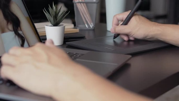 平面设计师在带有图形平板电脑的笔记本电脑上工作。润饰照片。