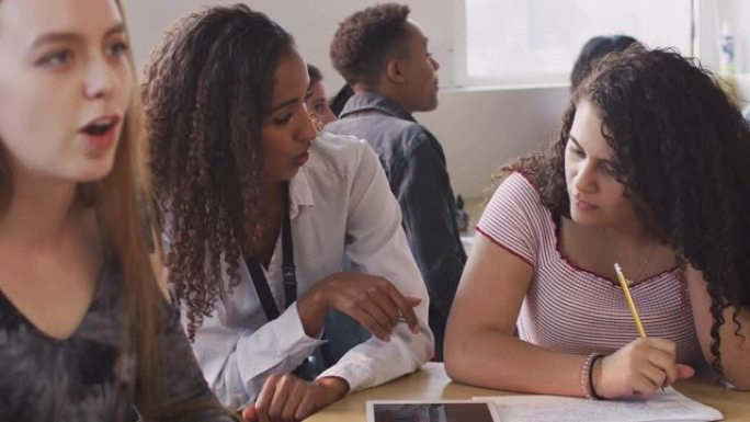 女教师为在数字平板电脑上工作的女学生提供一对一的支持