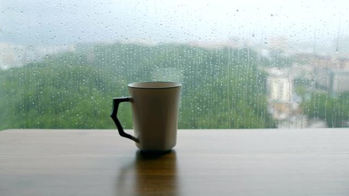 木制桌子上的咖啡杯，带有雨滴背景