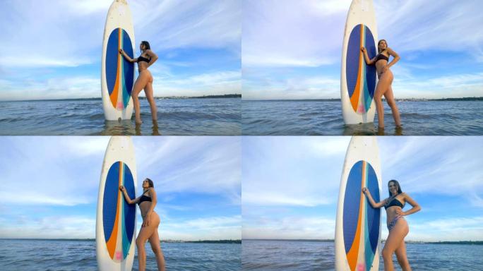 女运动员带着冲浪板站在水中，特写镜头。