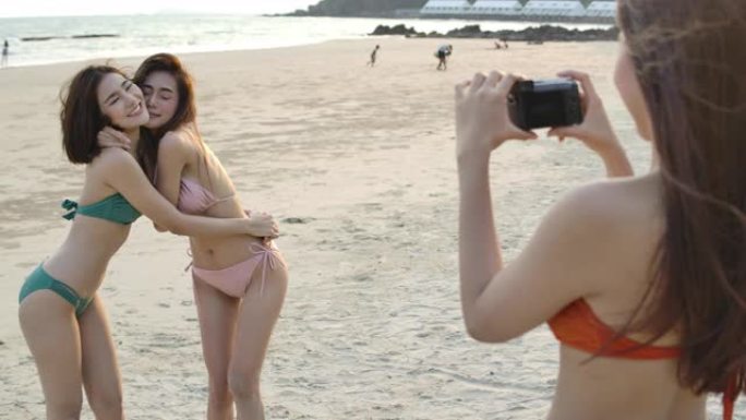 一群年轻女孩用单反相机时尚摄影在海滩上快乐假期摄影音乐派对拍照。慢动作。
