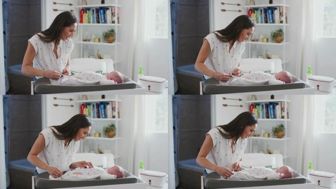 快乐妈妈在婴儿换衣桌上给家里刚出生的儿子换尿布，腰上