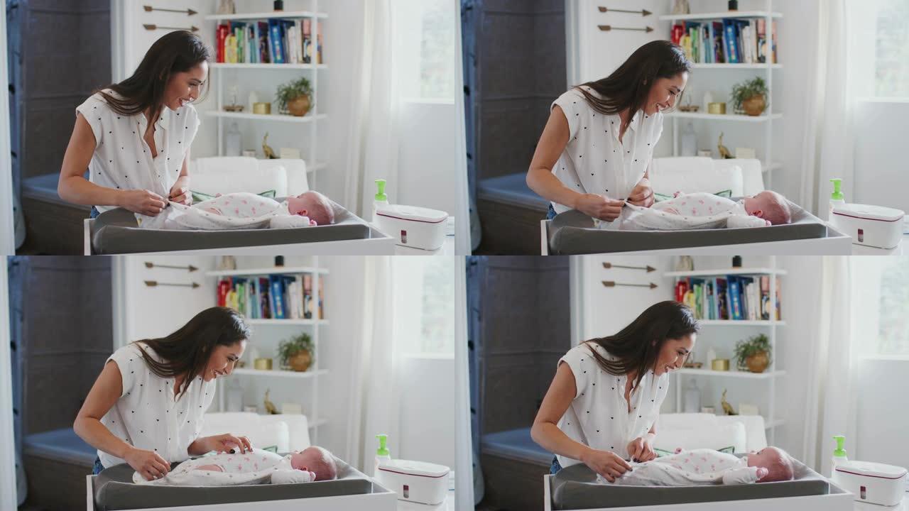 快乐妈妈在婴儿换衣桌上给家里刚出生的儿子换尿布，腰上