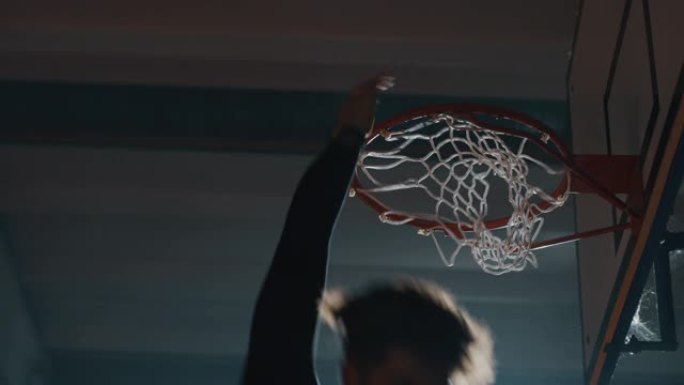 一名年轻职业男球员的电影慢动作镜头正在健身房进行篮球锻炼时扣篮