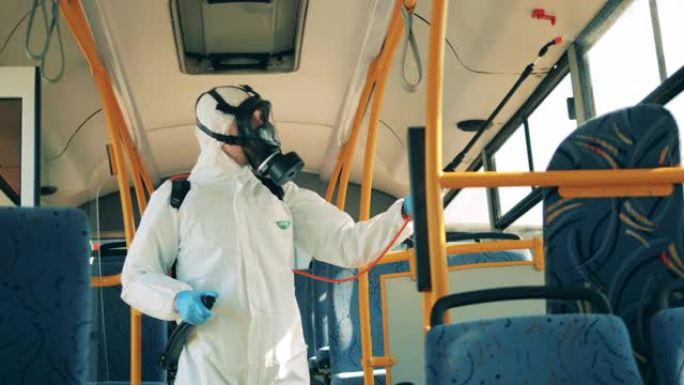 一个穿着危险品套装的人正在给公共汽车内部消毒。冠状病毒预防，卫生消毒过程。