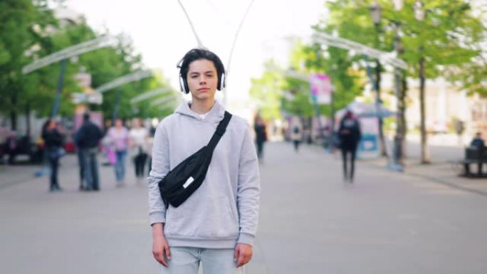 十几岁的男孩站在城市的耳机听音乐的延时