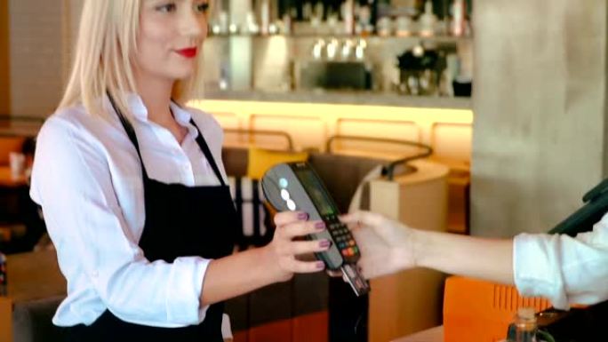 使用信用卡刷卡机支付的手特写。女人在刷卡机中输入信用卡代码。