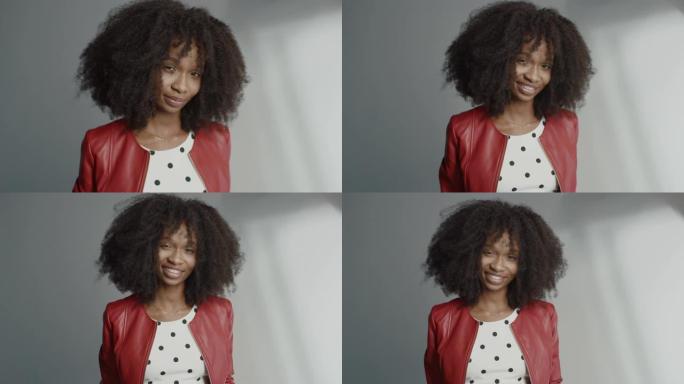 迷人的黑人女孩，郁郁葱葱的卷发摆姿势拍摄时尚杂志照片。美丽的女孩调皮地微笑，表演和玩面部表情。在专业