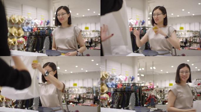 亚洲女孩在服装店用信用卡付款购买