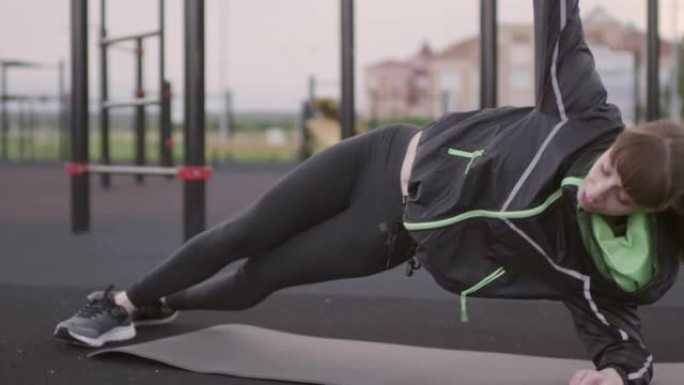 女运动员在室外健身场做侧木板臀部提升