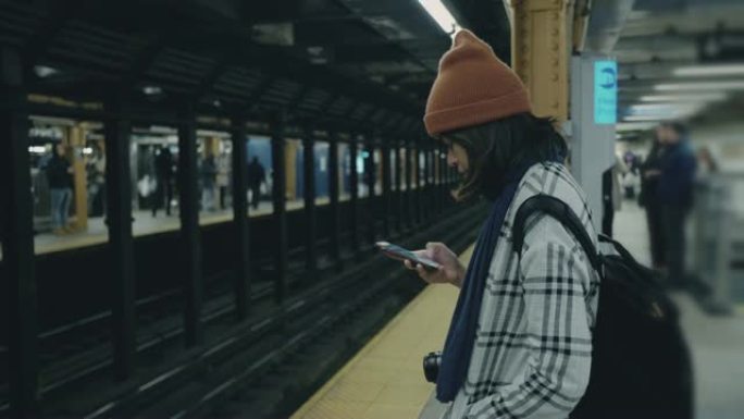在地铁站台上等待和发短信的旅游妇女
