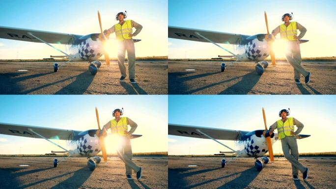 飞行员站在飞机附近的susnet背景上，靠近。