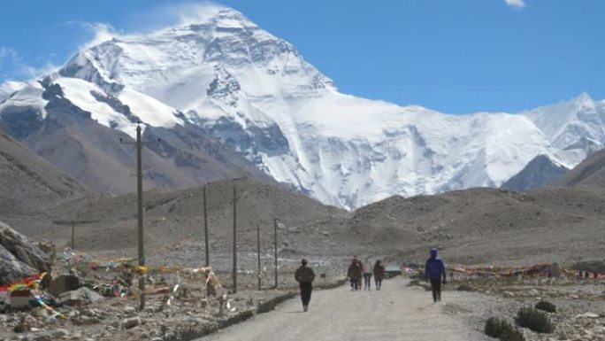 慢动作: 旅行者向风吹拂的珠穆朗玛峰徒步旅行的电影镜头。