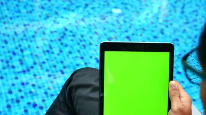 设计师在游泳池附近使用带绿屏的数字平板电脑