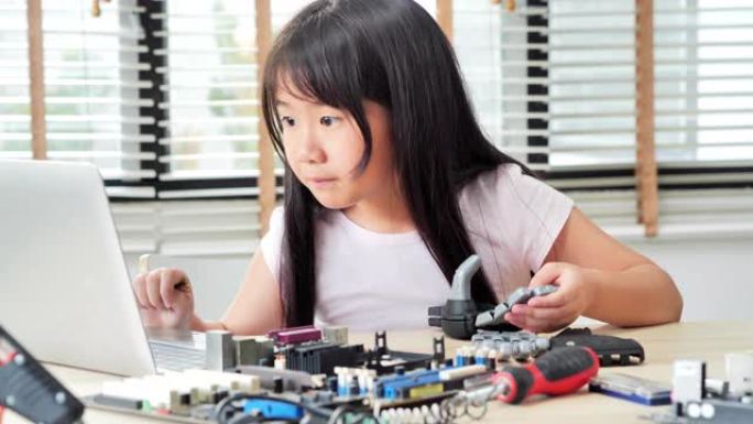 女孩在家中在计算机上进行构建和编程，并将其作为学校科学项目来构建机器人手臂。她对他的r work.e