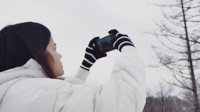 旅行者从山上通过智能手机拍摄冬季森林