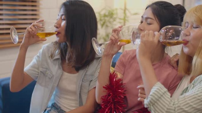 一群亚洲女性在家聚会，女性晚上在客厅的沙发上喝鸡尾酒聊天。青少年年轻朋友玩游戏，庆祝节日概念。慢动作