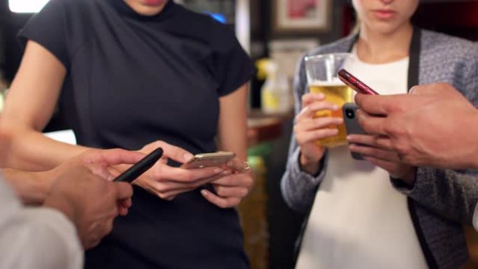 一群商业同事在酒吧喝酒时都在检查手机