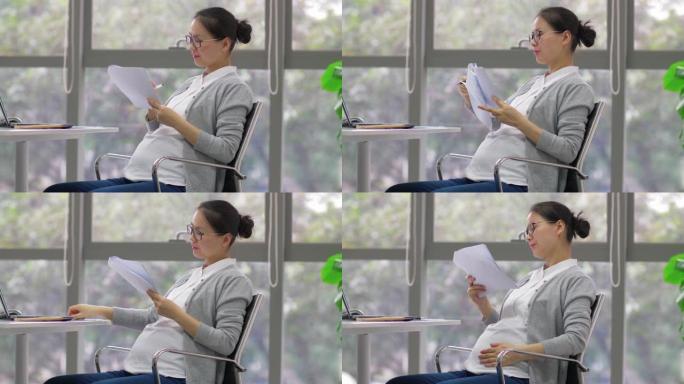 中国孕妇女商人在办公室工作的侧视图