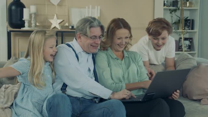 祖父母和孙子孙女正在使用笔记本电脑并大笑