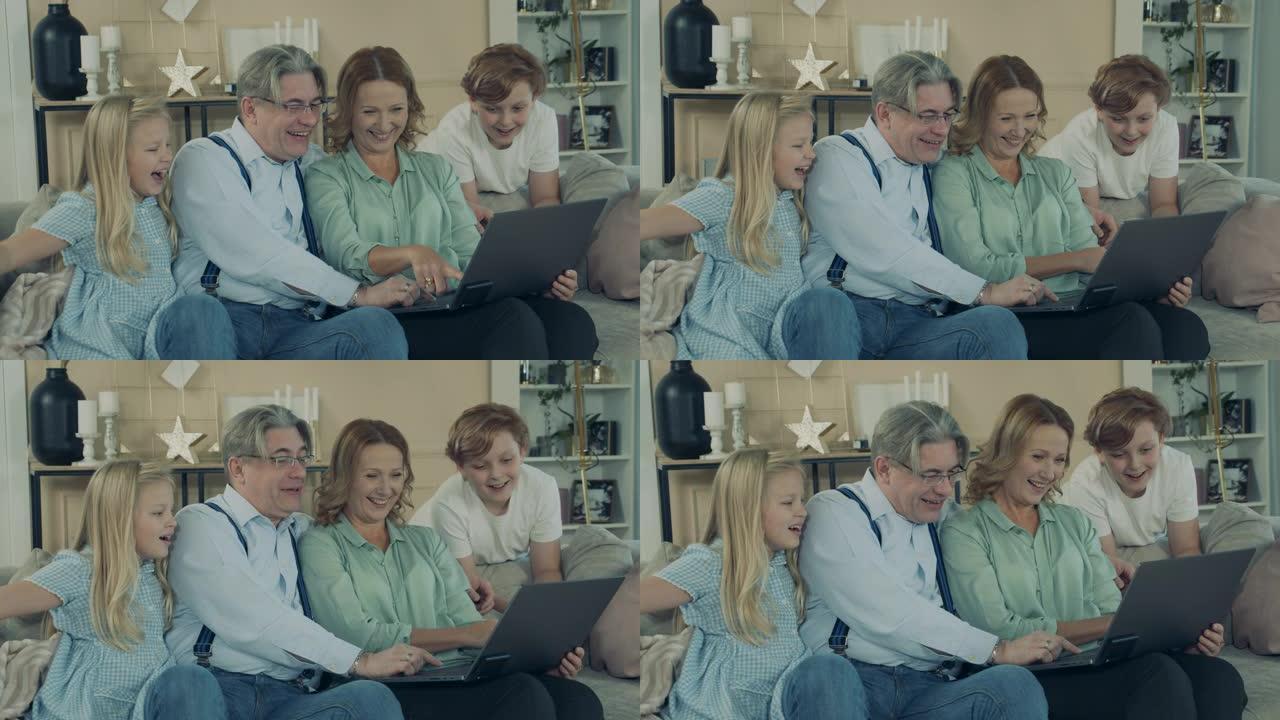 祖父母和孙子孙女正在使用笔记本电脑并大笑