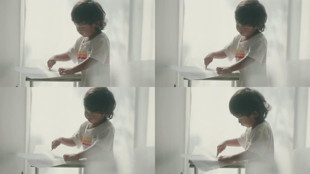 亚洲小男孩在家里的桌子上画他的故事。