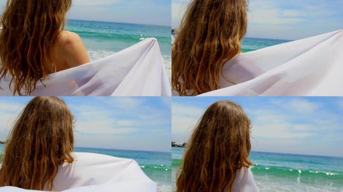 海滩4k上裹着纱笼的白人妇女的后视图