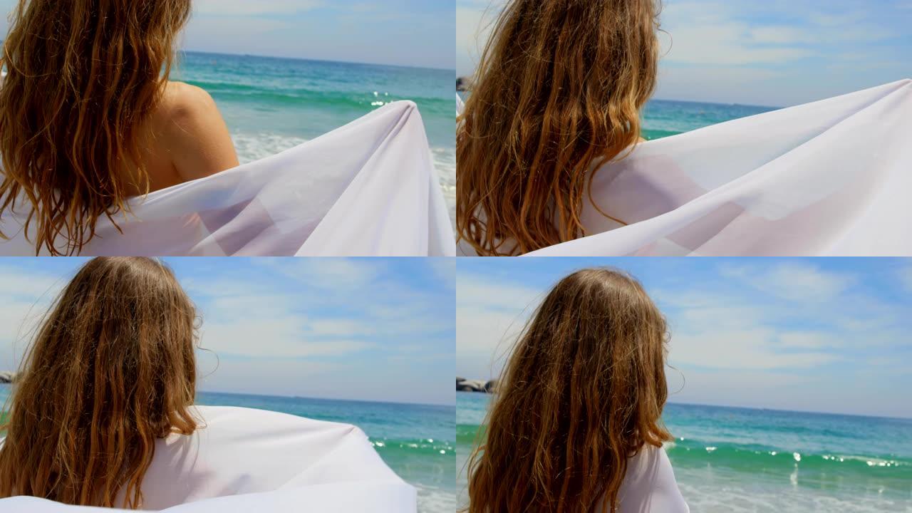 海滩4k上裹着纱笼的白人妇女的后视图
