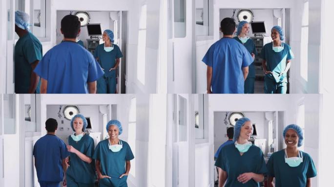 两名穿着磨砂膏的女外科医生在一起沿着繁忙的医院走廊行走时开会