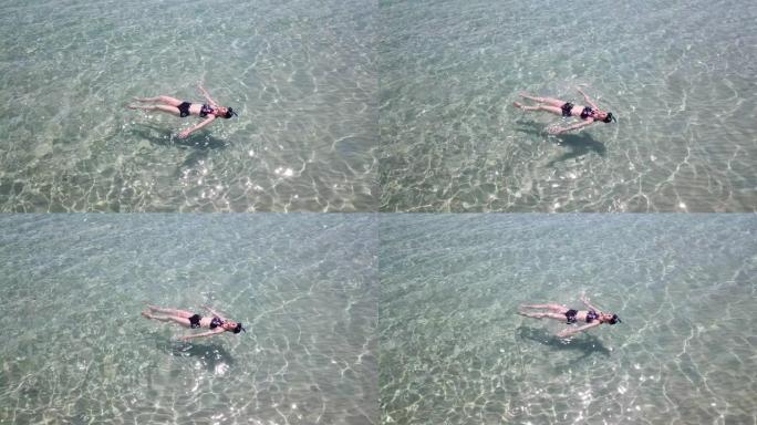 漂浮在晶莹剔透的大海中的亚洲妇女的鸟瞰图