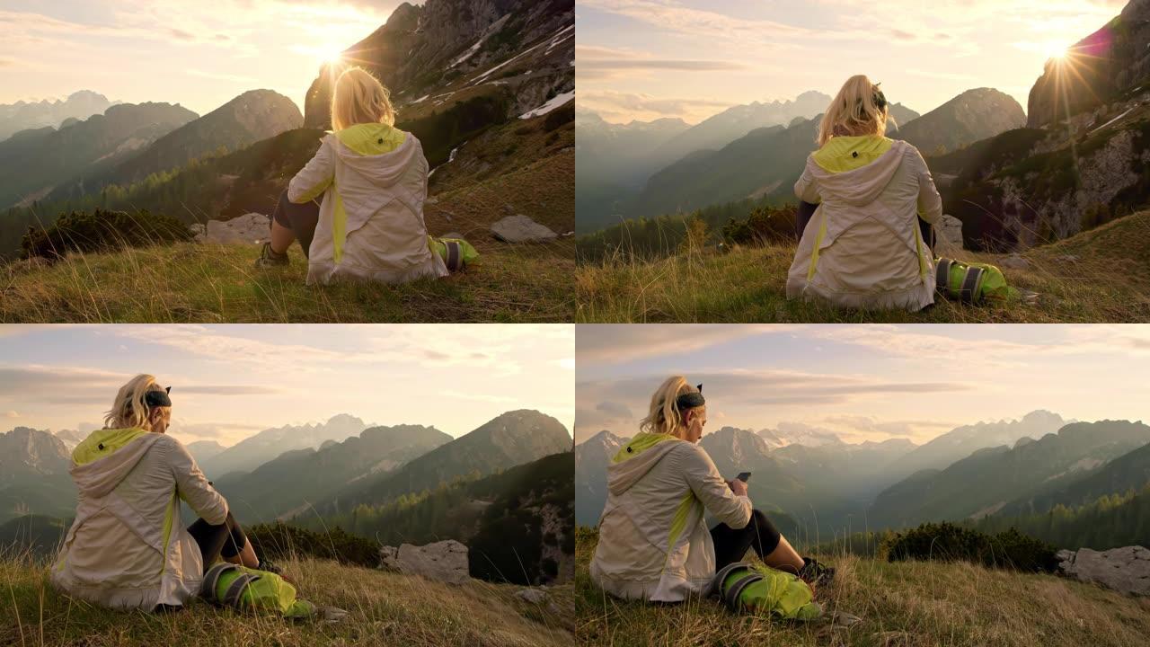MS女徒步旅行者休息，使用智能手机俯瞰阳光明媚，雄伟的山脉景观