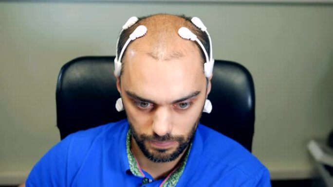 男子头上戴着机器人脑波扫描传感器，特写。