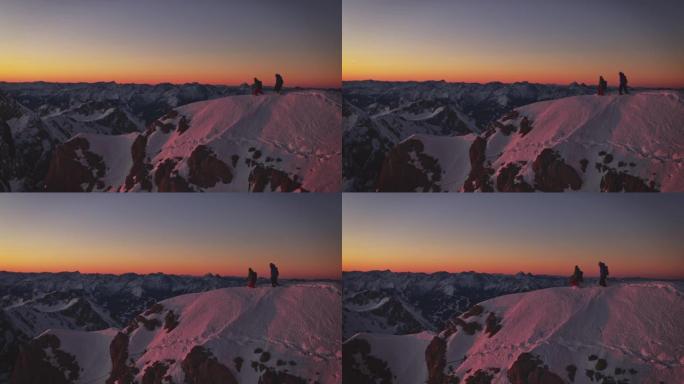 日出时在白雪覆盖的山脊上行走的男人