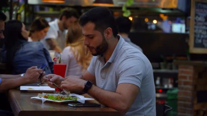 拉丁美洲男子独自在美食广场吃饭-食物和饮料概念