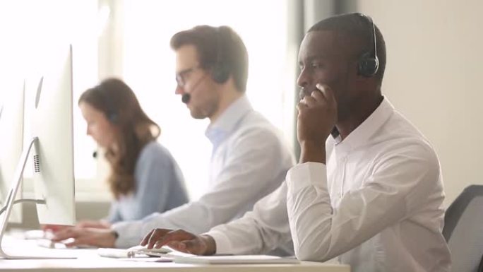 非洲男性呼叫中心工作人员戴着耳机远程帮助客户