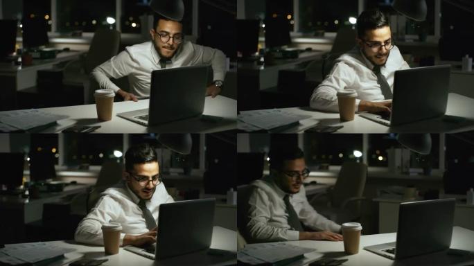 戴眼镜的商人晚上在办公室的笔记本电脑上工作