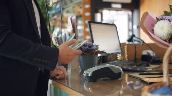 男性顾客用智能手机付款，然后从商店的花店取花