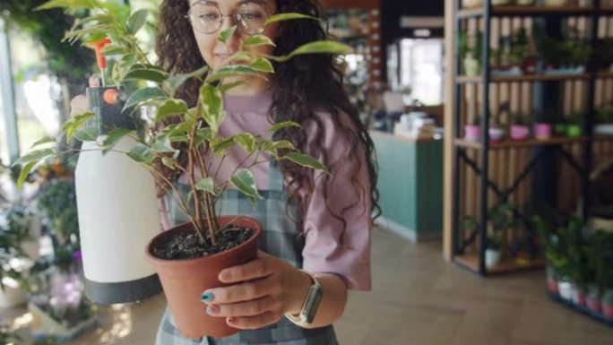 年轻女子花店在花店用水喷洒盆栽植物