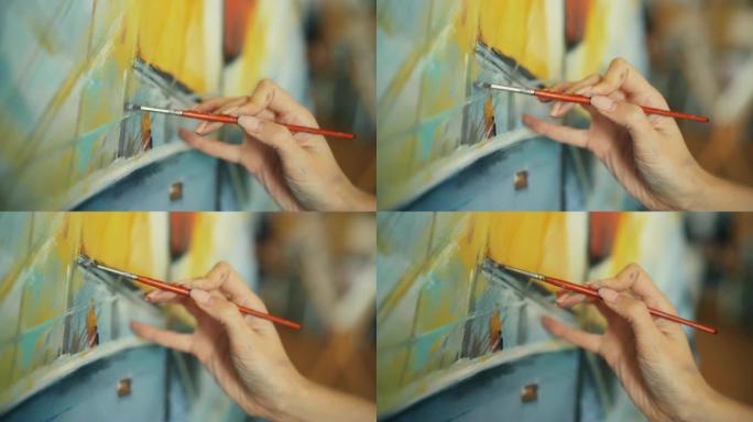 女性手握毛笔的特写镜头，用鲜艳的油画在画布上画美丽的图画。艺术性、创造性和人的概念。