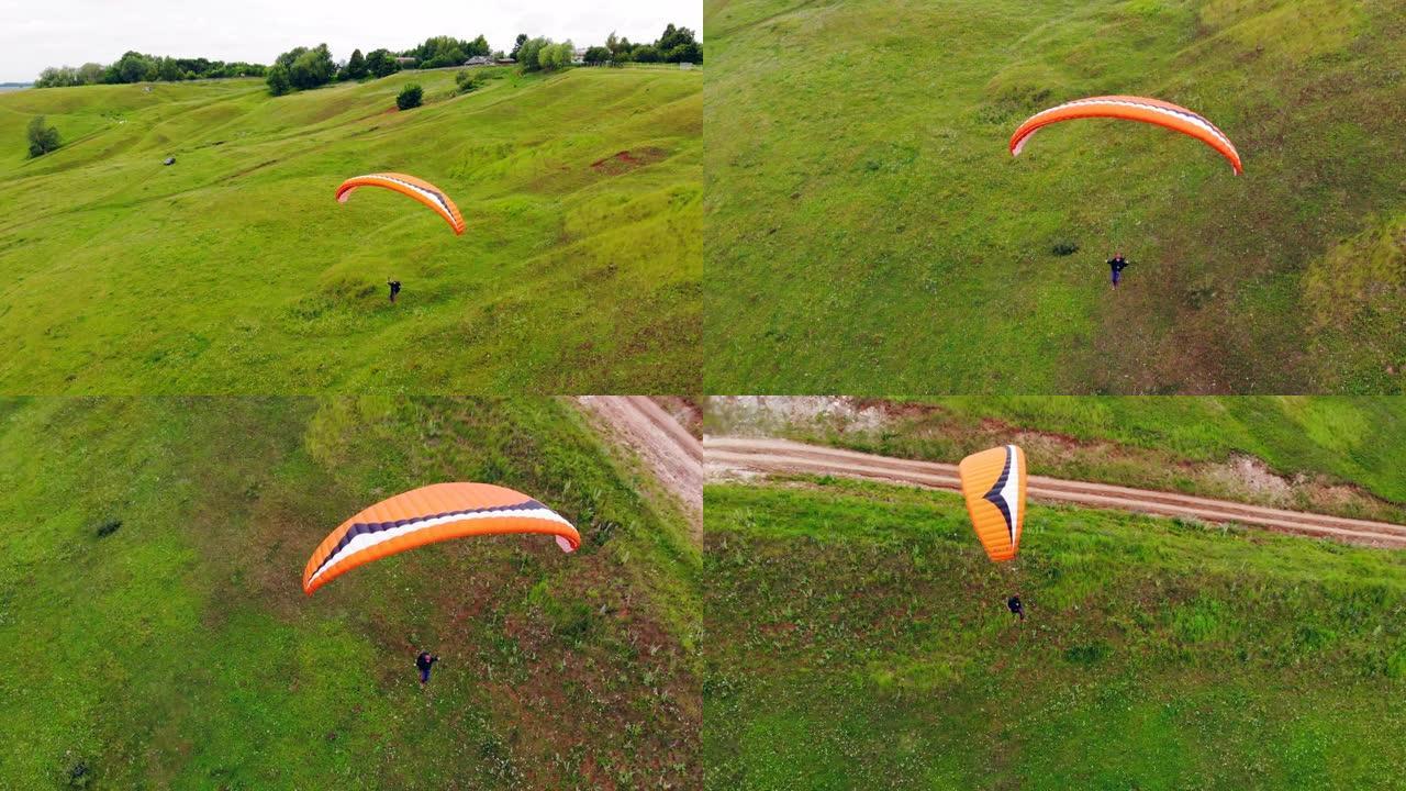 极限运动概念。一个人正在沿着绿色的草地飞行伞面