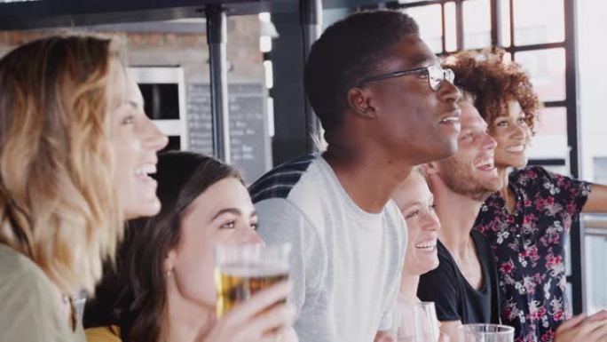 一群朋友在酒吧喝啤酒观看体育赛事并庆祝-慢动作拍摄