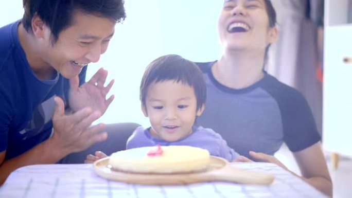 男孩和父母一起吹灭生日蜡烛。