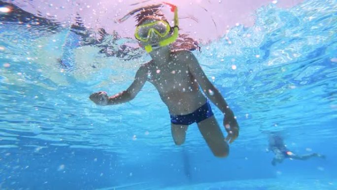 小男孩，孩子带着黄色面具在游泳池游泳。水下镜头。