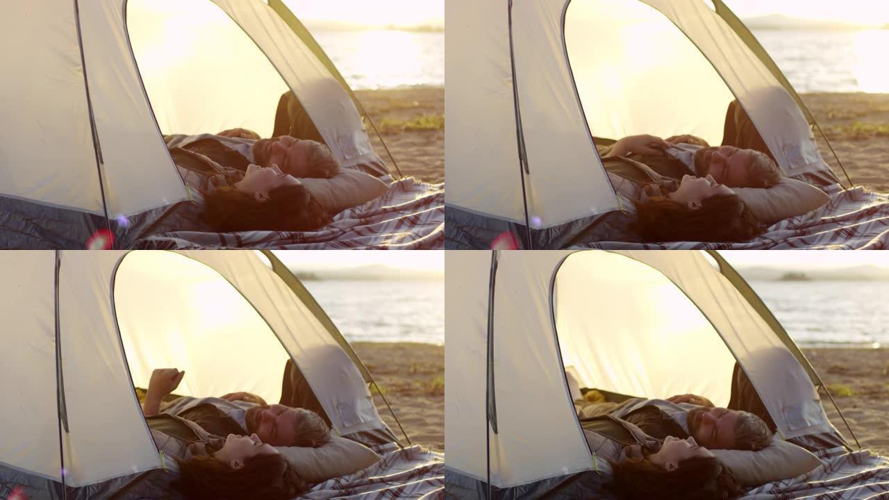 日落时分，浪漫的情侣躺在湖岸的帐篷里