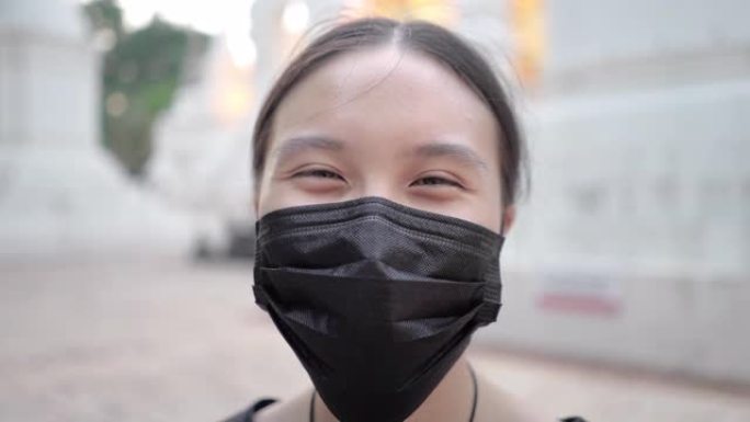 新型冠状病毒肺炎电晕病毒大流行期间，亚洲少女戴着黑色防护口罩微笑