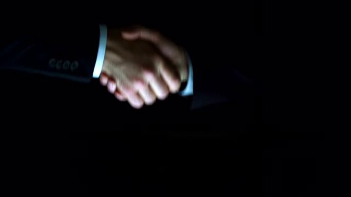 这两个人在黑暗的背景上握手。慢动作