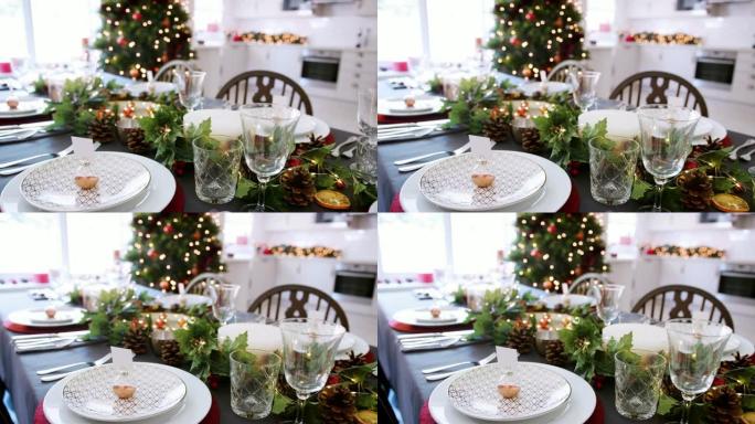 一个特写，缓慢的平移镜头，显示了一个节日的圣诞节餐桌，盘子上摆着摆设的名片持有人，绿色和红色的季节性