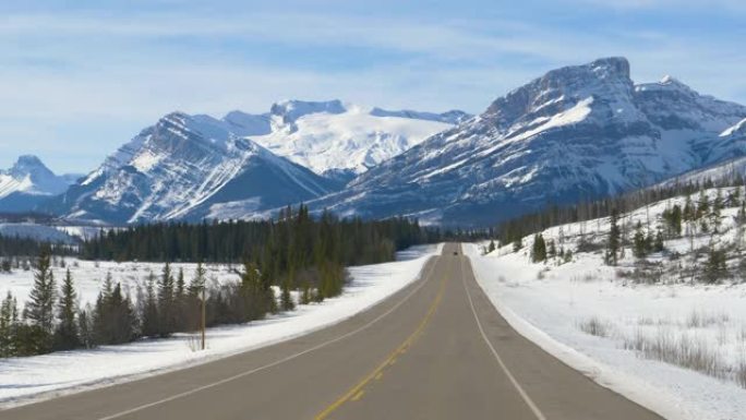 慢动作: 汽车消失在远处时，白雪皑皑的落基山脉的风景。